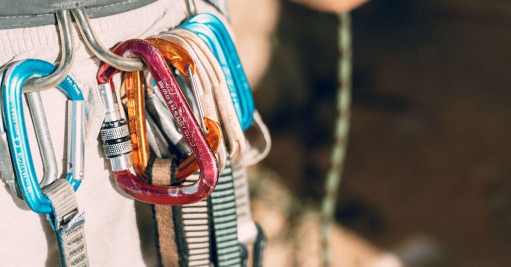 Detailed shot of climbing equipment with various carabiners attached to harness.